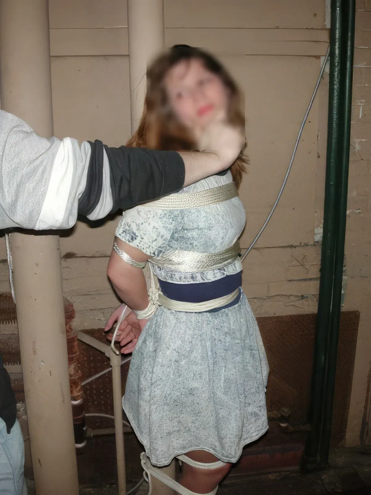 Blurred portrait of an adult restrained with tape around the torso and legs in an indoor setting